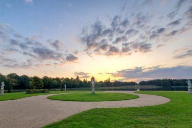 Gün batımında güzel bir manzara parkı, yaz gününde yeşil çimenler, bulutlu gökyüzü, batan güneş.