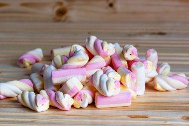 Bazı şekerlerin yakın plan fotoğrafı, çeşitli renkli jölelerin şeker dokusunu gösteriyor, ahşap bir arka planda fotoğraflanmış.