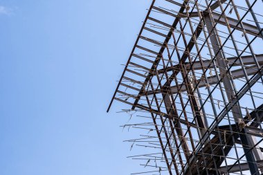 Mavi gökyüzündeki eski büyük bir evin metal iskeleti ilginç bir desen oluşturuyor.