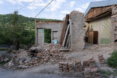 Gürcistan kırsalında eski bir taş ev sökülüyor, binanın içini görebiliyorsunuz çünkü dış duvarlar sökülmüş.