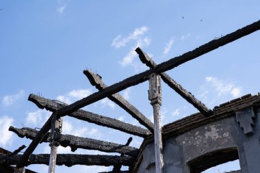 Mavi bir arka planda yanmış bir binanın iskeleti.