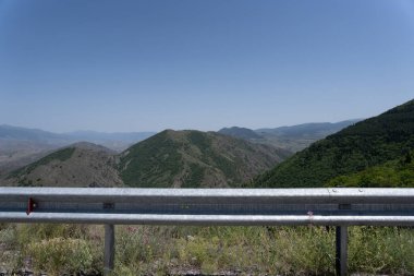 Yol kenarındaki bariyeri görebileceğiniz otoyoldan geniş bir ekin tarlası görünüyor.