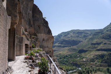 Gürcistan dağlarındaki manastırda dağ boyunca mağaralar ve geçitler var. Üzerlerinde mavi bir gökyüzü var.