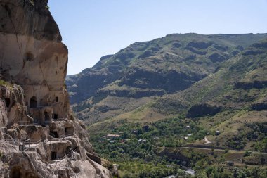 Gürcistan dağlarındaki manastırda dağ boyunca mağaralar ve geçitler var. Üzerlerinde mavi bir gökyüzü var.