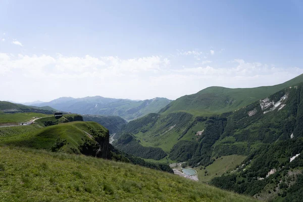 緑の山々と青い空に囲まれたジョージアの山々の美しい景色は 丘の下に水の体を見ることができます — ストック写真