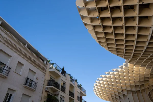 interesting building design that forms a different pattern and the background is a blue sky, but the other half of the gray building with balconies