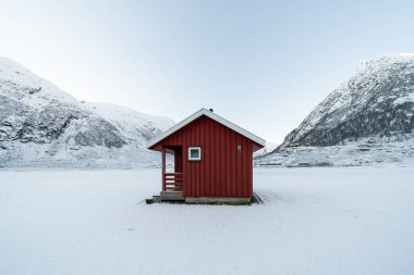 Norveç 'in karlı dağlarında kışın tahtalardan yapılmış kırmızı ahşap bir ev.