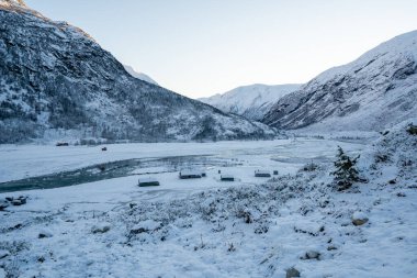 Dağlardan nehrin kıyısındaki küçük bir köye kış manzarası