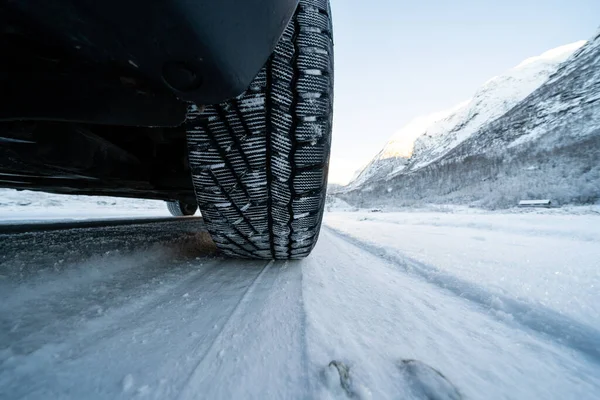 View from the bottom of the car on a snowy road where you can see the tread of a winter tire in the snow