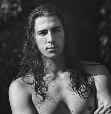 Çok uzun saçlı çekici bir adam vahşi doğada poz veriyor. Modelleme ve Moda Konsepti.
