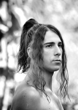 Çok uzun saçlı çekici bir adam vahşi doğada poz veriyor. Modelleme ve Moda Konsepti.