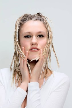 Sarışın afro örgülü sevimli genç kız izole edilmiş arka planda stüdyoda poz veriyor. Tarz, trendler, moda konsepti.
