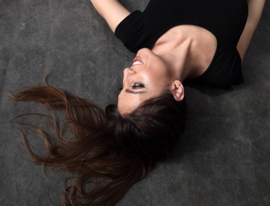 Güzel, pozitif esmer kız stüdyoda tuvalin arka planında poz veriyor. Rahatlama, zarafet, moda konsepti.