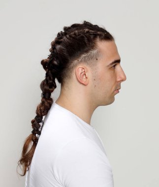 İzole edilmiş arka planda saç örgüleri olan şık bir erkek model. Tarz, saç stili, moda konsepti.