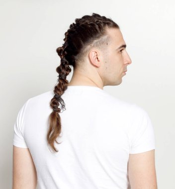 İzole edilmiş arka planda saç örgüleri olan şık bir erkek model. Tarz, saç stili, moda konsepti.