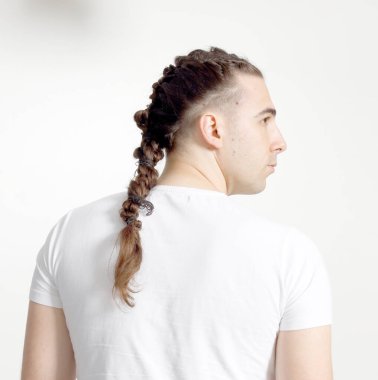 İzole edilmiş arka planda saç örgüleri olan şık bir erkek model. Tarz, saç stili, moda konsepti.