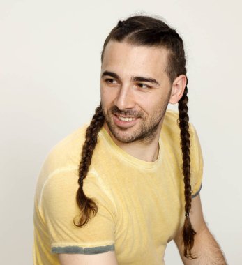 İzole edilmiş arka planda saç örgüleri olan şık bir erkek model. Tarz, saç stili, moda konsepti.