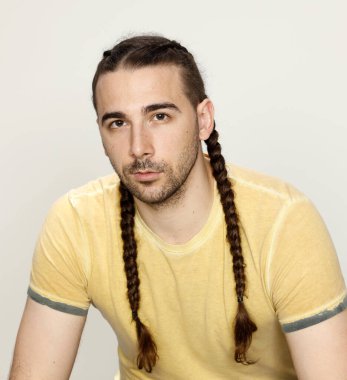 İzole edilmiş arka planda saç örgüleri olan şık bir erkek model. Tarz, saç stili, moda konsepti.