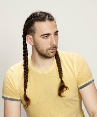 İzole edilmiş arka planda saç örgüleri olan şık bir erkek model. Tarz, saç stili, moda konsepti.