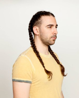 İzole edilmiş arka planda saç örgüleri olan şık bir erkek model. Tarz, saç stili, moda konsepti.