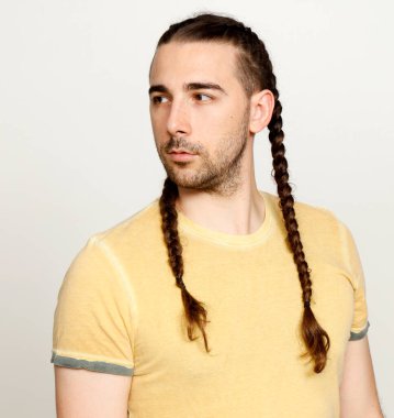 İzole edilmiş arka planda saç örgüleri olan şık bir erkek model. Tarz, saç stili, moda konsepti.