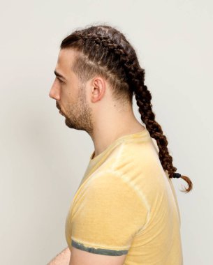 İzole edilmiş arka planda saç örgüleri olan şık bir erkek model. Tarz, saç stili, moda konsepti.