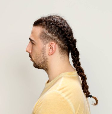 İzole edilmiş arka planda saç örgüleri olan şık bir erkek model. Tarz, saç stili, moda konsepti.