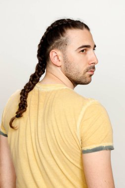 İzole edilmiş arka planda saç örgüleri olan şık bir erkek model. Tarz, saç stili, moda konsepti.