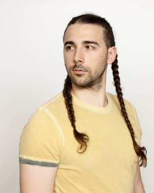 İzole edilmiş arka planda saç örgüleri olan şık bir erkek model. Tarz, saç stili, moda konsepti.