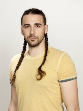 İzole edilmiş arka planda saç örgüleri olan şık bir erkek model. Tarz, saç stili, moda konsepti.