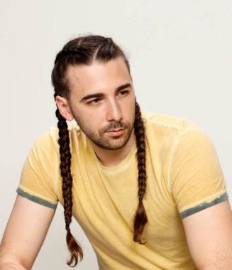 İzole edilmiş arka planda saç örgüleri olan şık bir erkek model. Tarz, saç stili, moda konsepti.