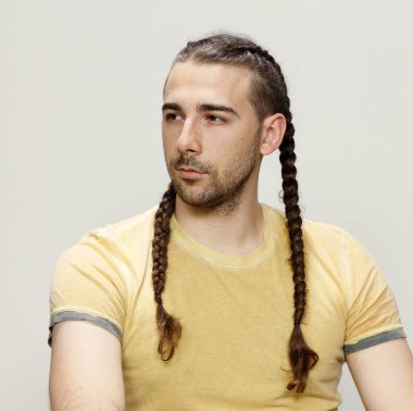 İzole edilmiş arka planda saç örgüleri olan şık bir erkek model. Tarz, saç stili, moda konsepti.