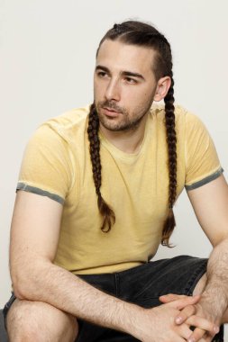 İzole edilmiş arka planda saç örgüleri olan şık bir erkek model. Tarz, saç stili, moda konsepti.