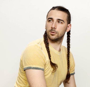 İzole edilmiş arka planda saç örgüleri olan şık bir erkek model. Tarz, saç stili, moda konsepti.