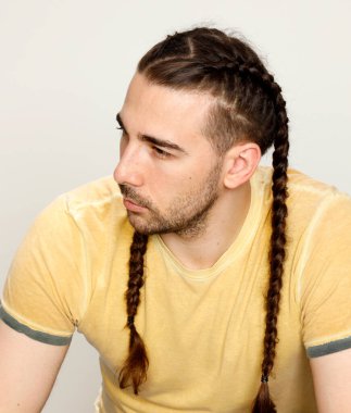 İzole edilmiş arka planda saç örgüleri olan şık bir erkek model. Tarz, saç stili, moda konsepti.