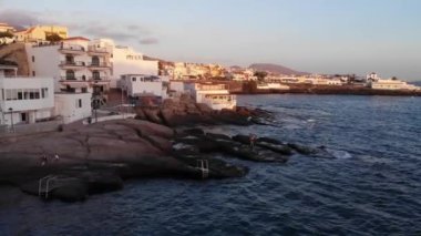 Tenerife, Canary Islands, Spain. September 2022: Aerial view on picturesque La Caleta village on sunset. Spanish destinations and resorts. La Caleta volcanic beach. 