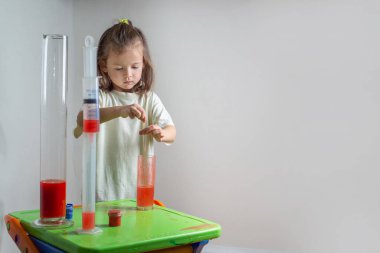 Çocuk renkli bir sıvıyı pipetle test tüpüne damlatıyor. Evde kimyasal bir deneyim. Evde eğitim ve uzak eğitim