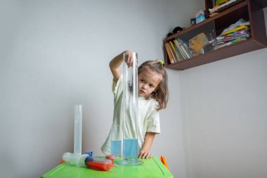 Çocuk renkli bir sıvıyı pipetle test tüpüne damlatıyor. Evde kimyasal bir deneyim. Evde eğitim ve uzak eğitim