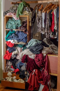 Giysilerle dolu kocaman bir dolap, baştan savma itilmiş ve raflara ve askılara asılmış. Gardırop dağınıklığı. Gardırop dağınıklığı.