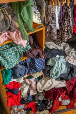 Giysilerle dolu kocaman bir dolap, baştan savma itilmiş ve raflara ve askılara asılmış. Gardırop dağınıklığı. Gardırop dağınıklığı.