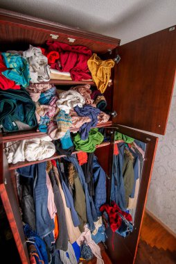 Elbiseleri askılarda ve açık çekmecelerde olan açık gardırop.