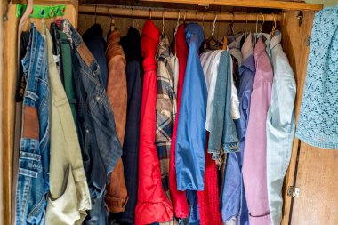 Askılarda ve çekmecelerde eski ve yeni kıyafetler var. İkinci el tekrar kullanım. Dolabın temizlenmesi ve temizlenmesi