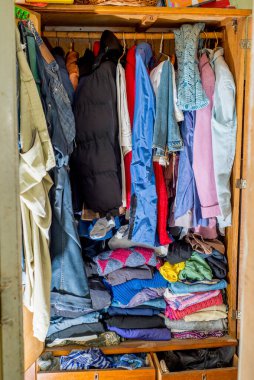 Askılarda ve çekmecelerde eski ve yeni kıyafetler var. İkinci el tekrar kullanım. Dolabın temizlenmesi ve temizlenmesi