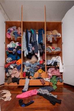 Gardırop dağınıklığı. Giysilerle dolu bir gardırop. Yere saçılmış giysiler.