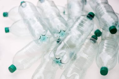 Beyaz arka planda bir yığın buruşmuş plastik şişe.