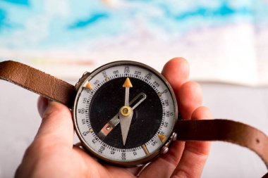 Parlak bir dünya haritasının arka planına karşı elinde pusula