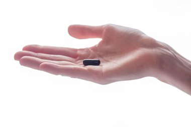 Kadın avucundaki kapsülde bir tablet var.