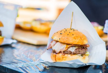 Eldivenli satıcının ellerinde hazır burger.