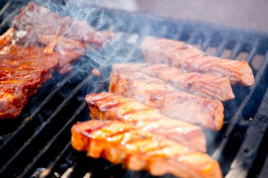 Izgara balık bifteği. Somon parçaları açık ateşte kızarır. Ateş ve duman balık parçalarının üzerinde yuvarlanıyor.