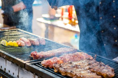 Barbekü kaburgaları. Eldivenli eller ızgarada kızarmış kaburgaları sollar.